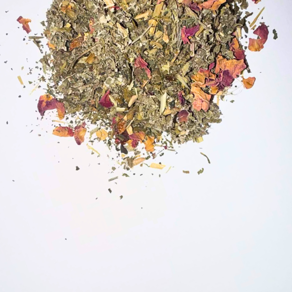 A pile of loose-leaf herbal tea with dried flowers and botanicals, photographed on a clean white background.